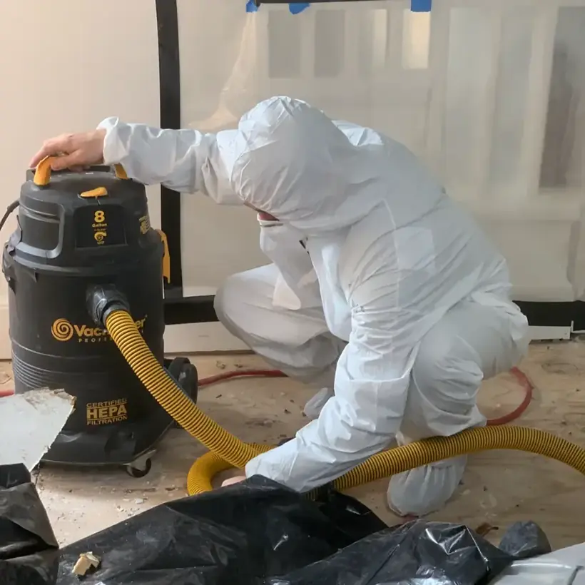 Technician in a protective suit running a HEPA vacuum during a contaminated water cleanup in Columbia, MD